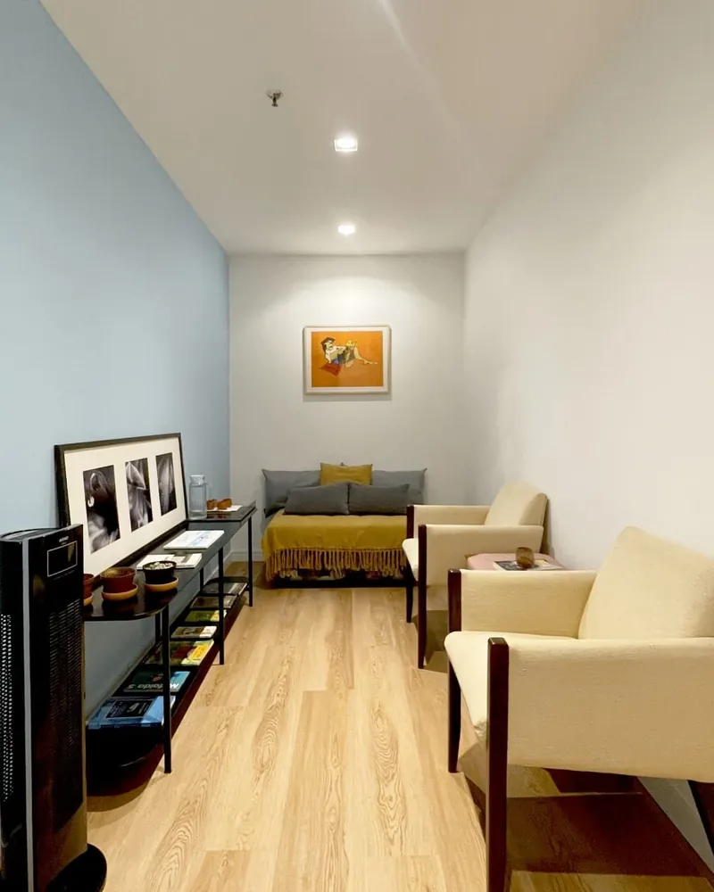 Sala do consultório com poltronas, sofá e quadros na parede